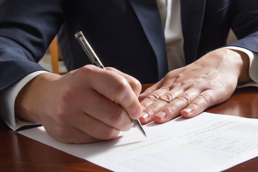 Photo of a person writing papers on the table-desk